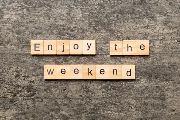 Enjoy the weekend word written on wood block. Enjoy the weekend text on cement table for your desing, Top view concept.