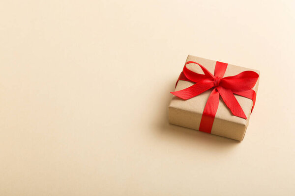 Wrapped christmas or other holiday handmade present in craft paper with colored ribbon. Present box, decoration of gift on table, top view with copy space.
