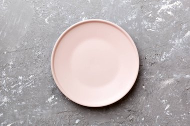 Çimento arka planındaki boş pembe tabağın üst görüntüsü. Tasarımın için boş boşluk.