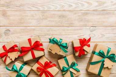 wrapped christmas or other holiday handmade present in paper with colored ribbon. Present box, decoration of gift on colourfull table, top view with copy space.