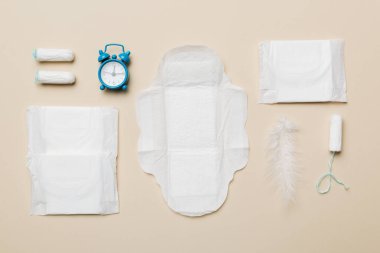 Alarm saatini hijyenik kadın tamponları ve regl pedleri ile çalıyor. Tıbbi konsept kadın kritik günler ve regl dönemi. Kadın günlük hijyen. Boşluğu kopyala.