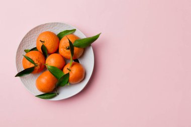 Taze kesilmiş mandalinalar ve renkli arka planda yuvarlak tabaklar. Yemek ve içecek malzemeleri hazırlanıyor. Sağlıklı beslenme teması üst görünüm kopyalama alanı.