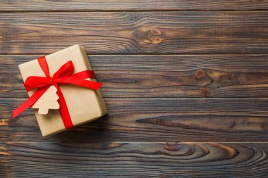 wrapped christmas or other holiday handmade present in paper with colored ribbon. Present box, decoration of gift on colourfull table, top view with copy space.