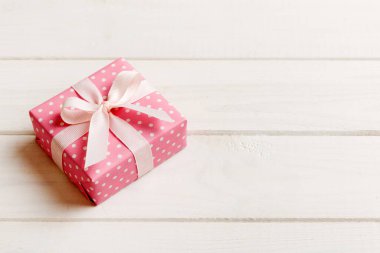 Noel 'i ya da diğer tatil hediyelerini renkli arka planda kurdeleyle renkli kağıda sardım. Şimdiki kutu, renkli tabloda hediye süslemesi, kopya alanı ile üst görünüm.