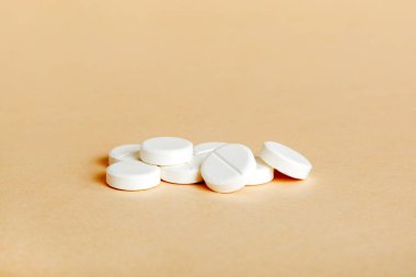 Renkli arka planda bir yığın beyaz hap. Tabletler masaya saçılmış. Kırmızı yumuşak jelatin kapsül yığını. Vitaminler ve beslenme takviyeleri konsepti.