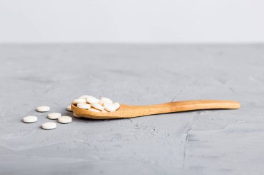Renkli arka planda bir yığın beyaz hap. Tabletler masaya saçılmış. Kırmızı yumuşak jelatin kapsül yığını. Vitaminler ve beslenme takviyeleri konsepti.