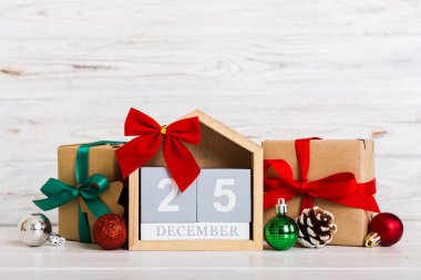 25 december. Christmas composition on colored background with a wooden calendar, with a gift box, toys, bauble copy space.