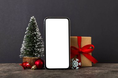 Digital phone mock up with rustic Christmas decorations for app presentation with empty space for you design. Christmas online shopping concept. Tablet with copy space on colored background.