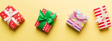 Renkli kağıda sarılı ve renkli arka planda konfetiyle süslenmiş hediye kutularıyla tatil dairesi yatıyordu. Noel, Doğum günü, Sevgililer Günü ve satış konsepti, üst manzara.