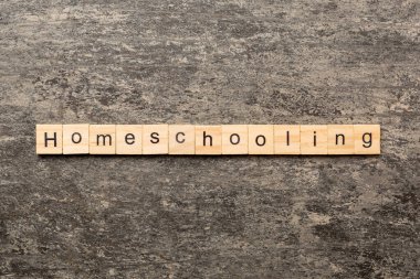 Ahşap blokta evde eğitim kelimesi yazıyor. Masada ev eğitimi metni, konsept.