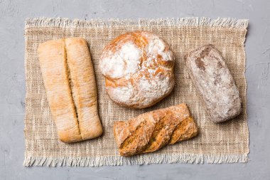Kırsal masa manzaralı peçeteli taze pişmiş ekmek çeşitleri. Sağlıklı mayasız ekmek. Fransız ekmeği.