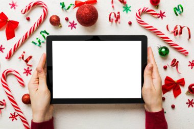 Evden Noel alışverişi, kadın elleri boş beyaz ekranlı tableti tutuyor. Kadın elinde tablet, boş ekran, Noel ağacı ve arka planda hediyeler..