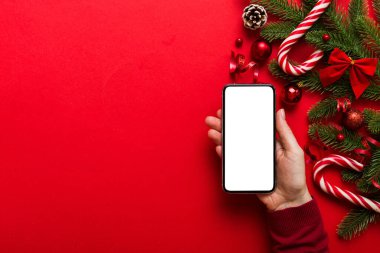 Mesaj atmak için yeri olan bir Noel modeli. Noel reklamı, uygulama şablonu. Masa arkasında boş ekran olan el ele tutuşan telefon. Mutlu yıllar ve Xmas Flat.