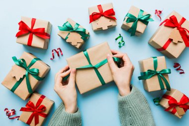 Kadınlar Noel tatili için sürpriz hediyeler hazırlıyor. İş yerinde el aletleri ve manzarayla oturuyor. Renkli masada Noel hediyesini paketleyen kadın..