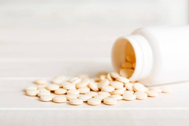 İlaç şişesi ve beyaz haplar arka plana dökülmüş. İlaçlar ve reçeteli haplar arka plandaydı. İlaç şişesinden beyaz ilaç ve haplar dökülüyor..