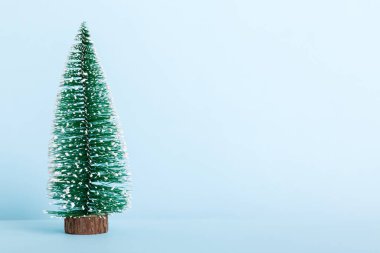 One small Christmas tree on colored background. new year decoration with copy space.