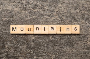 Ahşap bloğa yazılmış bir kelime. Dağlar çimento masa üzerinde metin desing, konsept için.