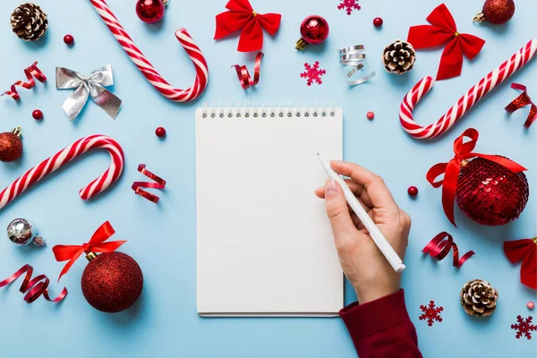 Frau Schreibt Weihnachtswunschliste Auf Notizbuch Auf Farbigem Hintergrund Mit Weihnachtsdekoration — Stockfoto