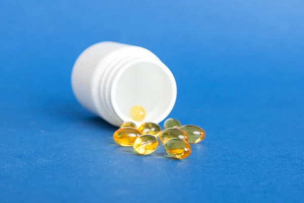 Soft gels pills with Omega-3 oil spilling out of pill bottle close-up. Gel capsules bottle white surface. Omega 3, multivitamins, Calcium, antibiotics. Health. Immunity.