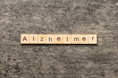 Tahta blokta Alzheimer kelimesi yazıyor. Alzheimer metni çimento masasında desing, konsept için.