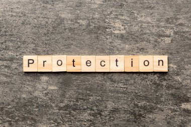 Tahta bloğa yazılmış bir kelime. Deksing, konsept için çimento tablo üzerinde PROTECTION metin.