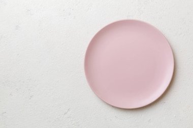 Çimento arka planındaki boş pembe tabağın üst görüntüsü. Tasarımın için boş boşluk.