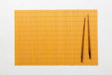 Çimento arka planında iki çubuk ve bambu paspas. Üst görünüm, alanı kopyala.