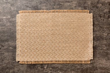 Çimento arka planında yiyecek için kahverengi masa örtüsünün üst görüntüsü. Tasarımın için boş boşluk.