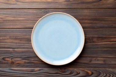 Ahşap zemindeki boş mavi tabağın üst görüntüsü. Tasarımın için boş boşluk.