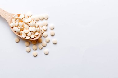 Renkli arka planda bir yığın beyaz hap. Tabletler masaya saçılmış. Kırmızı yumuşak jelatin kapsül yığını. Vitaminler ve beslenme takviyeleri konsepti.