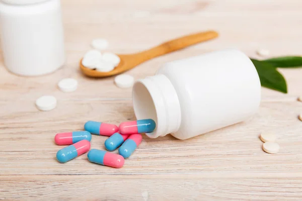 different drugs and health supplement pills poured from a medicine bottle health care and medical top view on colored background.