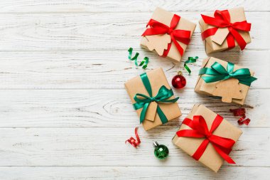 wrapped christmas or other holiday handmade present in paper with colored ribbon. Present box, decoration of gift on colourfull table, top view with copy space.