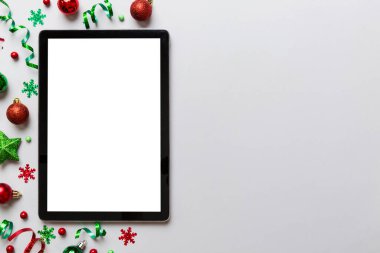 Noel alışverişi boş beyaz ekranlı tablet bilgisayardan yapılıyor. Renkli arka planda noel süsleme toplarıyla fotokopi alanı olan tablet. Kış tatillerinde satış geçmişi.