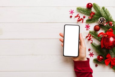 Mesaj atmak için yeri olan bir Noel modeli. Noel reklamı, uygulama şablonu. Masa arkasında boş ekran olan el ele tutuşan telefon. Mutlu yıllar ve Xmas Flat.
