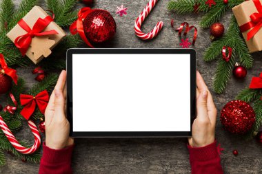 Evden Noel alışverişi, kadın elleri boş beyaz ekranlı tableti tutuyor. Kadın elinde tablet, boş ekran, Noel ağacı ve arka planda hediyeler..