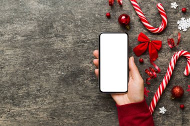 Mesaj atmak için yeri olan bir Noel modeli. Noel reklamı, uygulama şablonu. Masa arkasında boş ekran olan el ele tutuşan telefon. Mutlu yıllar ve Xmas Flat.