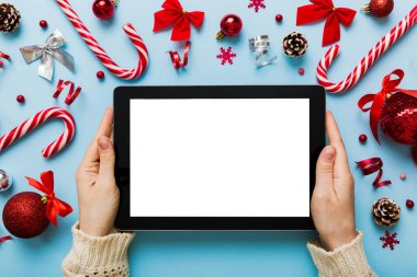 Evden Noel alışverişi, kadın elleri boş beyaz ekranlı tableti tutuyor. Kadın elinde tablet, boş ekran, Noel ağacı ve arka planda hediyeler..