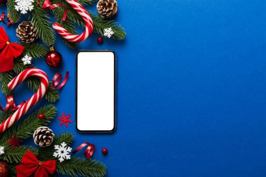 Mesaj atmak için yeri olan bir Noel modeli. Noel reklamı, uygulama şablonu. Masa arkasında boş ekran olan el ele tutuşan telefon. Mutlu yıllar ve Xmas Flat.