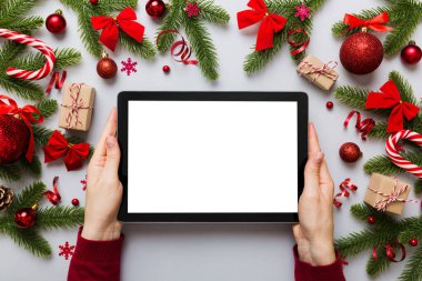 Evden Noel alışverişi, kadın elleri boş beyaz ekranlı tableti tutuyor. Kadın elinde tablet, boş ekran, Noel ağacı ve arka planda hediyeler..