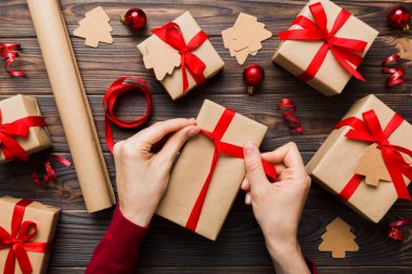 Kadınlar Noel tatili için sürpriz hediyeler hazırlıyor. İş yerinde el aletleri ve manzarayla oturuyor. Renkli masada Noel hediyesini paketleyen kadın..