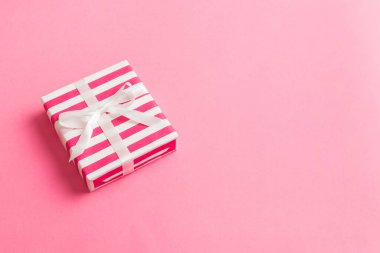 Noel 'i ya da diğer tatil hediyelerini renkli arka planda kurdeleyle renkli kağıda sardım. Şimdiki kutu, renkli tabloda hediye süslemesi, kopya alanı ile üst görünüm.