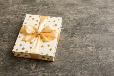 Noel 'i ya da diğer tatil hediyelerini renkli arka planda altın kurdeleli beyaz kağıda sardım. Şimdiki kutu, renkli tabloda hediye süslemesi, kopya alanı ile üst görünüm.