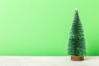 One small Christmas tree on colored background. new year decoration with copy space.