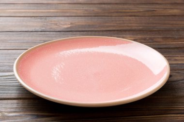 Ahşap arka planda boş pembe plaka manzarası. Tasarımın için boş boşluk.