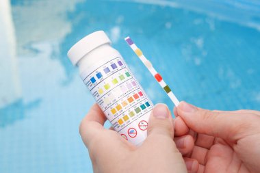 Yazın yüzme havuzundaki PH ve klor analizi. Test şeridi ile suyun kalitesini kontrol et, sonuçları karşılaştır.