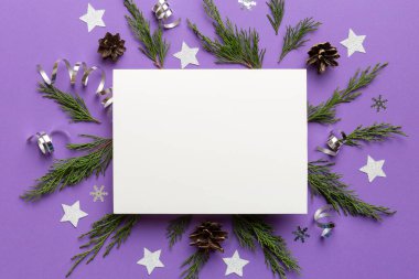 Noel kompozisyonu düzdü. Kare kağıt boş, çam ağacı dalları, renkli arka planda noel süslemeleri. Üst görünüm, metin için boşluk kopyala.