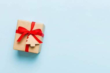 wrapped christmas or other holiday handmade present in paper with colored ribbon. Present box, decoration of gift on colourfull table, top view with copy space.