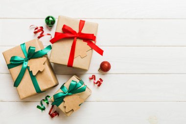 wrapped christmas or other holiday handmade present in paper with colored ribbon. Present box, decoration of gift on colourfull table, top view with copy space.