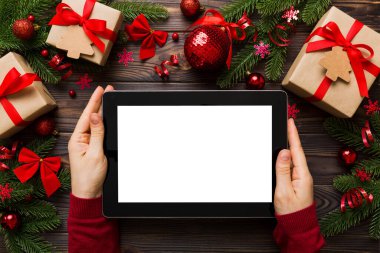 Evden Noel alışverişi, kadın elleri boş beyaz ekranlı tableti tutuyor. Kadın elinde tablet, boş ekran, Noel ağacı ve arka planda hediyeler..