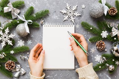 Noel 'i yazmak için bir kadın not defterine Xmas dekorasyonlu renkli arkaplan çiziyor.